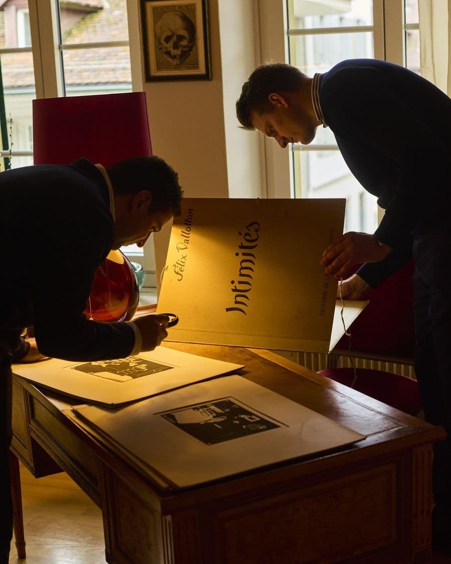 Elia Himmelreich und Sander Jongbloed prüfen die Holzschnittmappe Intimités von Félix Vallotton im Auktionshaus Zofingen