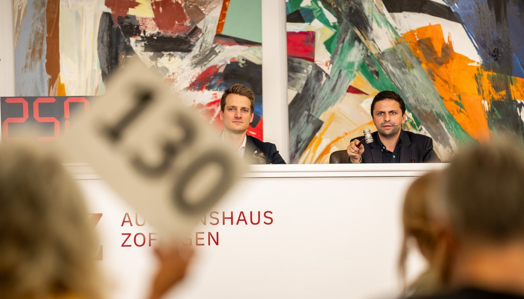 Saalauktion im Auktionshaus Zofingen — Elia Himmelreich mit dem Hammer am Auktionatorenpult, im Vordergrund eine Bieterkarte